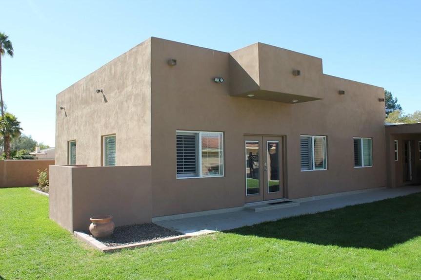 Tan stucco flat-roof house with lawn